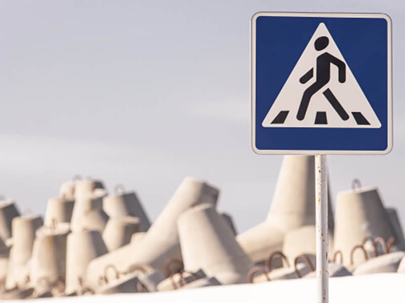 Знак пешеходный переход на фоне бетонных блоков
